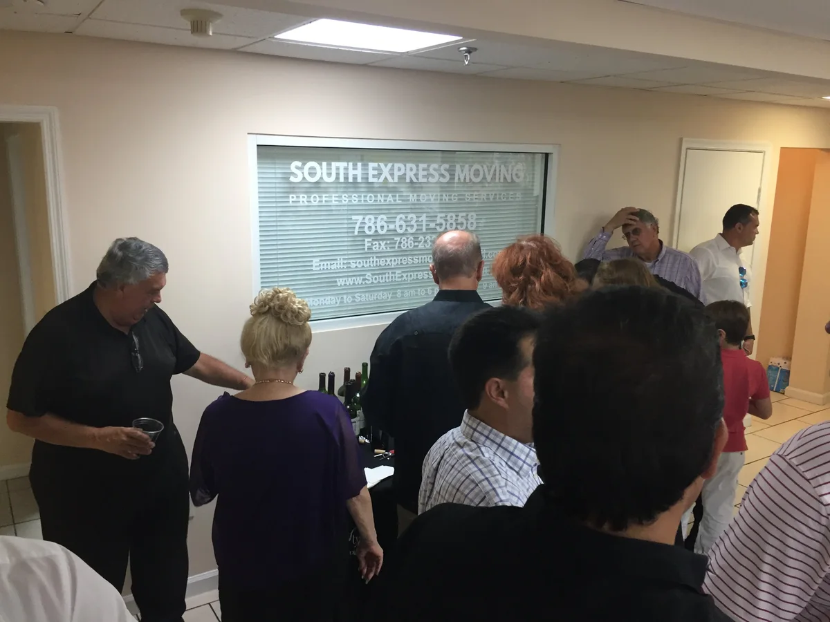 Invitados durante un evento de South Express Moving con el nombre de la empresa visible en la ventana de la oficina